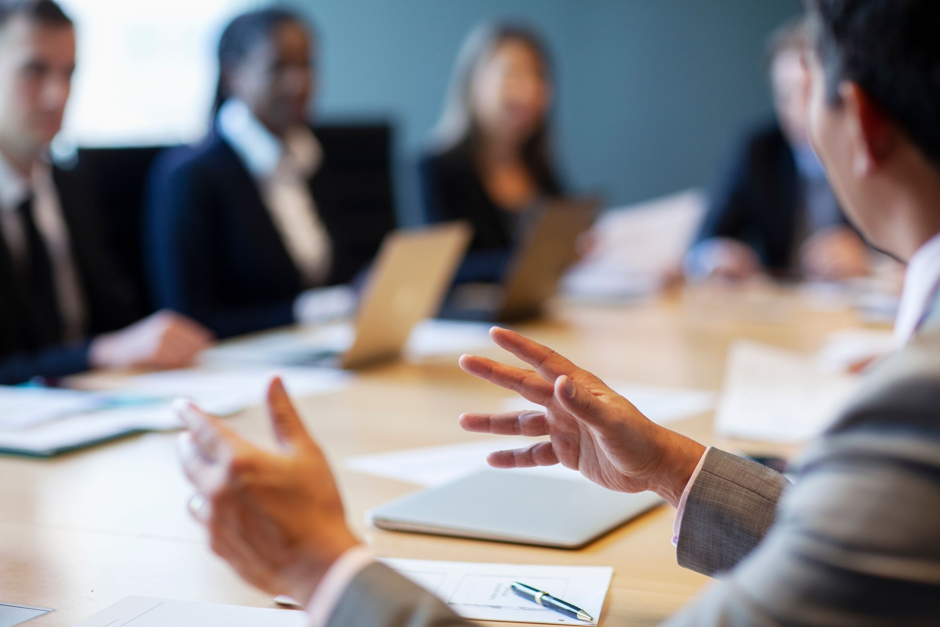 Hands of businessman gesturing ideas decisions in business meeting with group of work colleagues at board room conference table