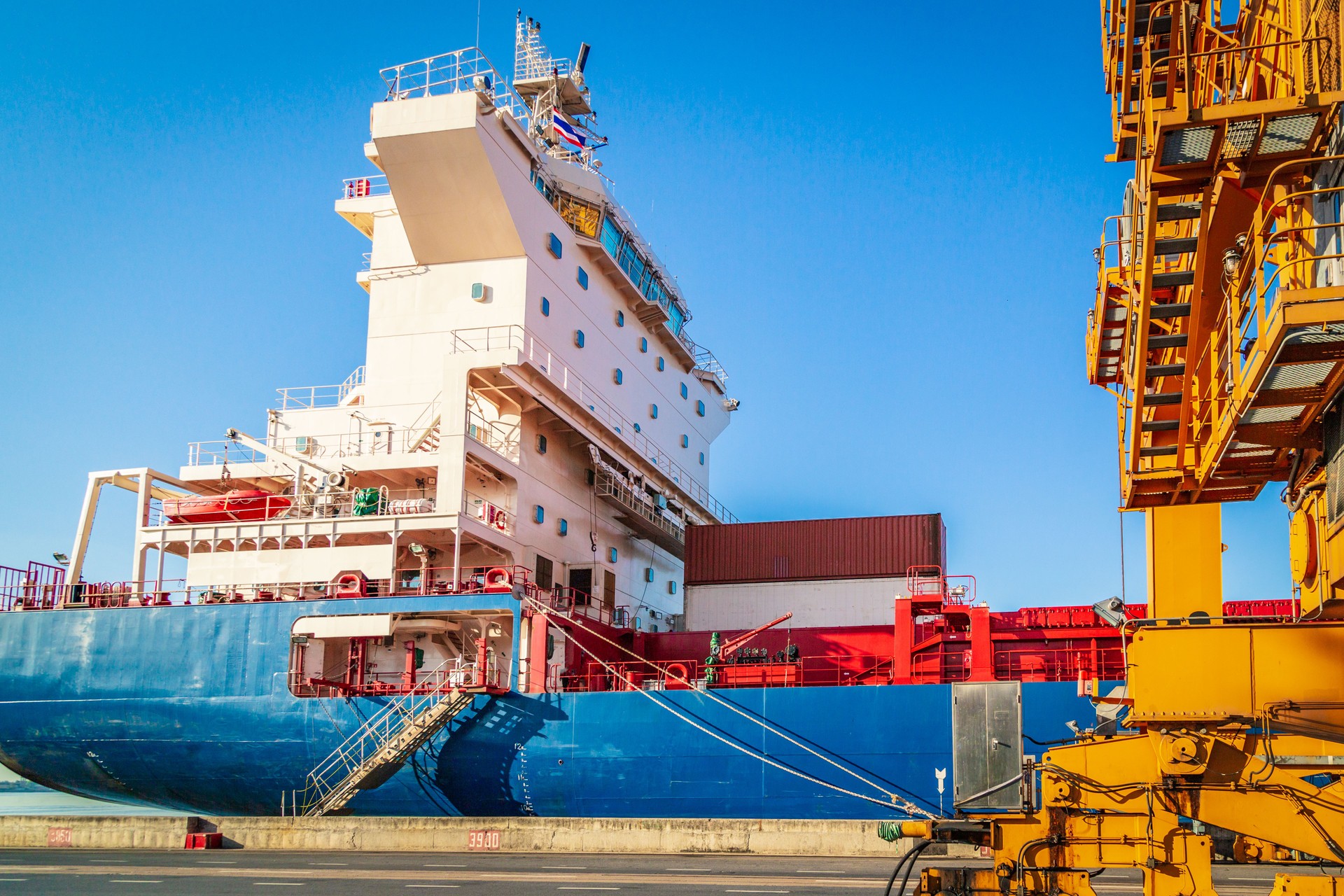 Container Cargo freight ship with working crane in shipyard