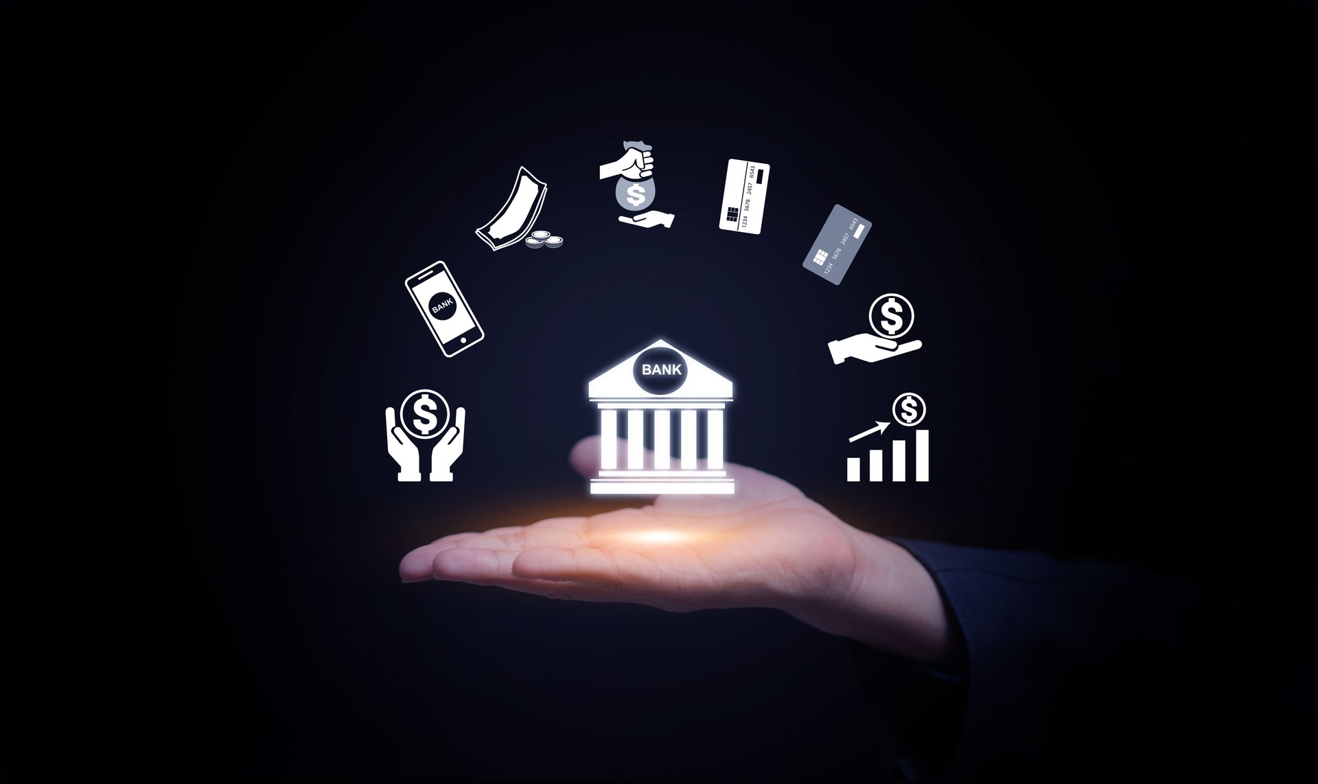 Hand holding digital bank icon with floating finance symbols, mobile payment, credit card, money management, fintech, and online transaction technology for modern financial services.